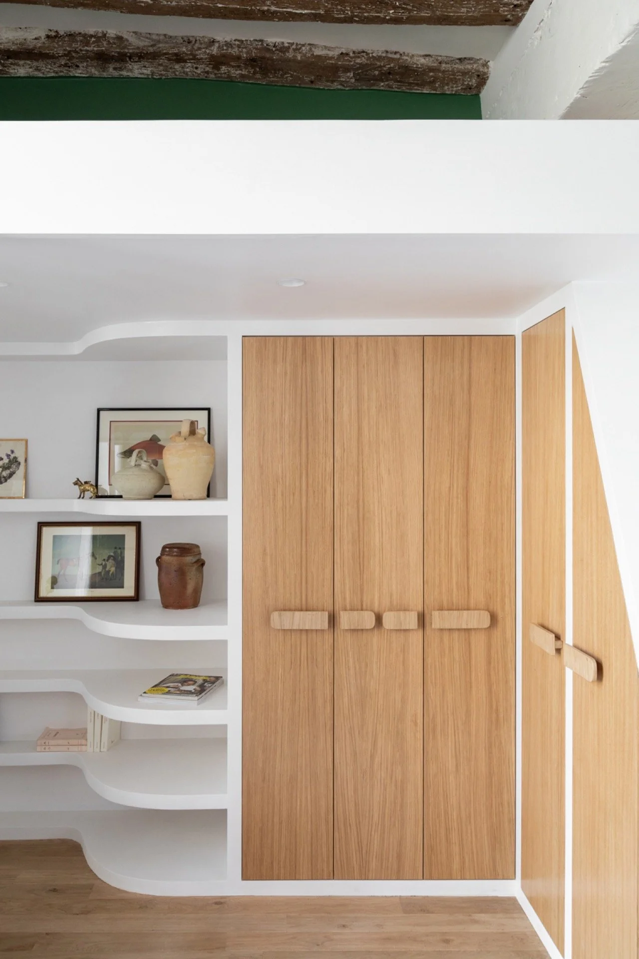 Une étagère blanche avec des objets décoratifs et un placard en bois dans une pièce moderne.