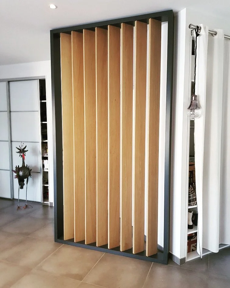 Une pièce avec un panneau en bois japonais ou à claire-voie, noir autour, devant un mur blanc et un sol en carreaux beige.