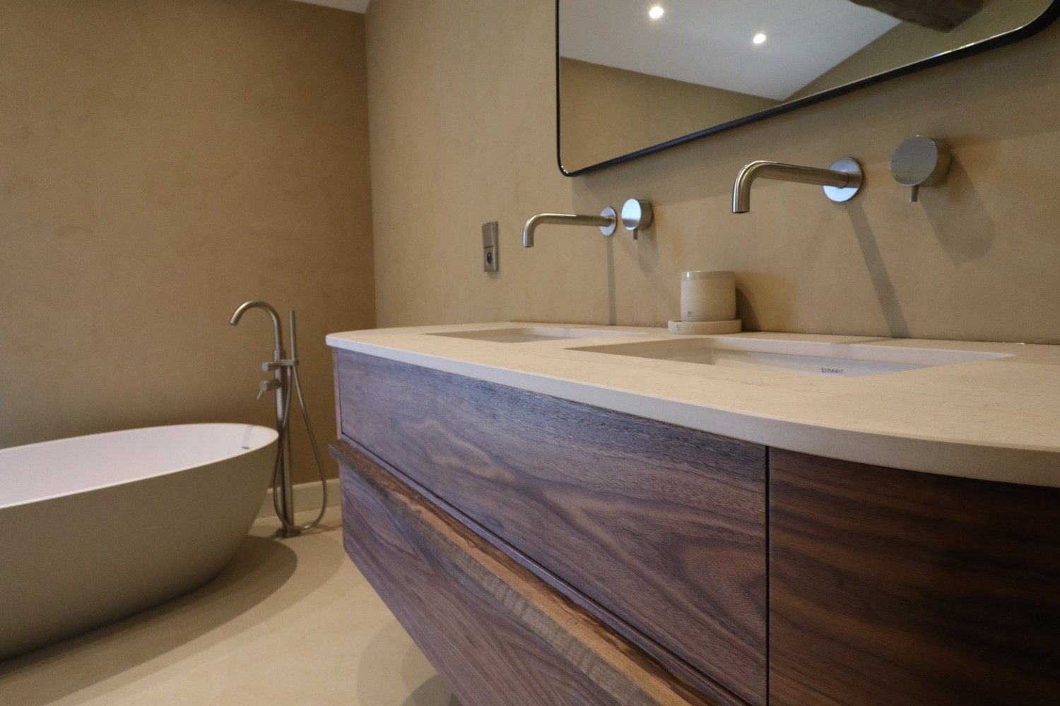 Bain de baignoire blanc et double lavabo en pierre dans une salle de bain moderne avec miroir.