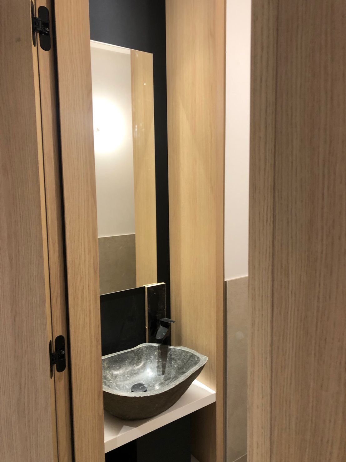 Petit lavabo en pierre noire dans une salle de bain avec un miroir et un mur noir
