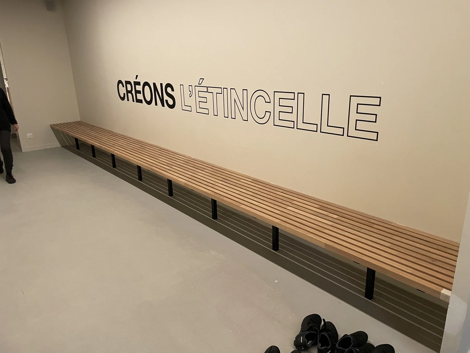 Long wooden bench against a wall with the text "CRÉONS L'ÉTINCELLE" written on the wall.