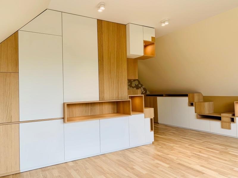 Facade intérieure avec rangement en bois clair et blanc, sous un plafond en pente.