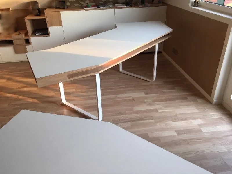 Deux bureaux modernes en bois et blanc dans une pièce lumineuse.